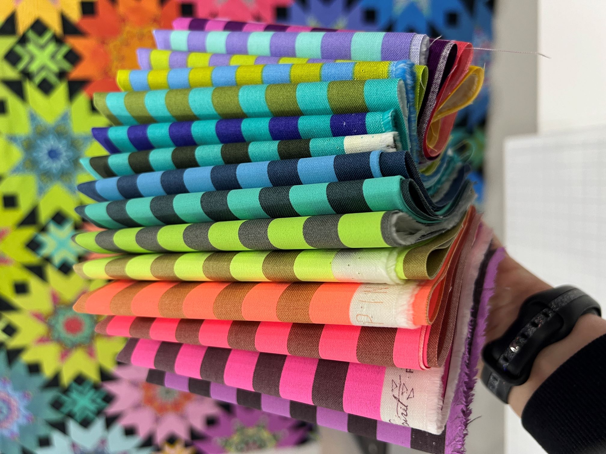 A hand holding up a stack of colorful paper straws.