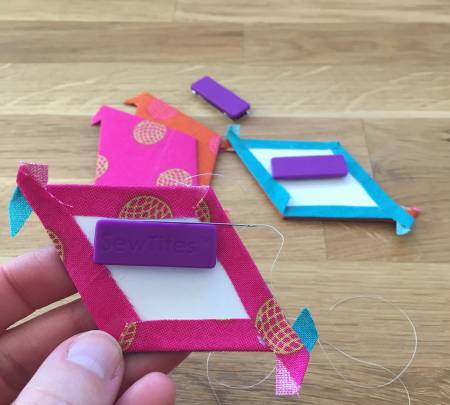 A person holding up a piece of paper with an erasers stuck on it.