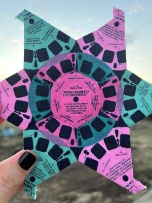 A person holding up a star shaped paper disc.