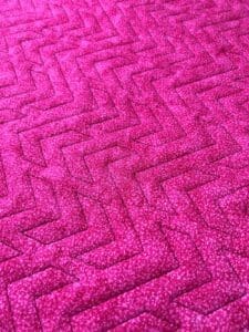 Close-up of a pink textured carpet with a zigzag pattern.
