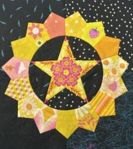 Colorful quilted star and flower pattern on dark fabric.