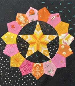 Colorful quilt block featuring a central star and petal shapes.