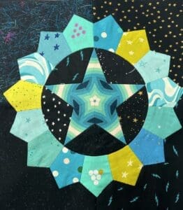 A colorful star-shaped fabric quilt block with various blue and yellow patterns.