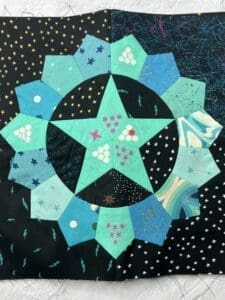 Star-shaped quilt with various blue and green fabric patches.