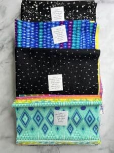 Three folded fabric pieces with distinct colorful patterns stacked.
