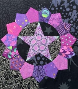 A vibrant quilt with purple, pink, and black geometric patterns.
