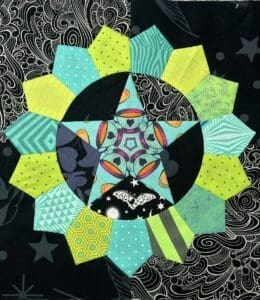 Colorful geometric star quilt block on patterned fabric.