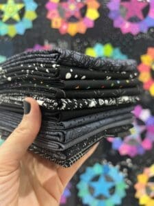 Hand holding a stack of black and white patterned fabric squares.