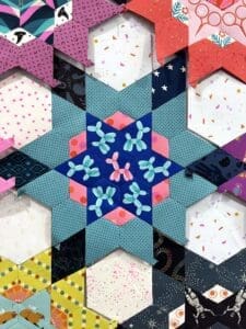 Colorful star quilt pattern made of hexagonal fabric pieces.