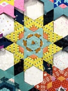 Colorful geometric quilt pattern with stars and triangles.