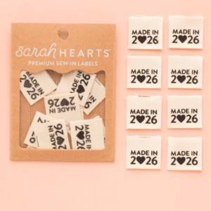 Cute heart-shaped pins with "Made in 2026" text and various symbols.
