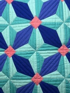 Close-up of a colorful quilt with geometric patterns in blue and pink.